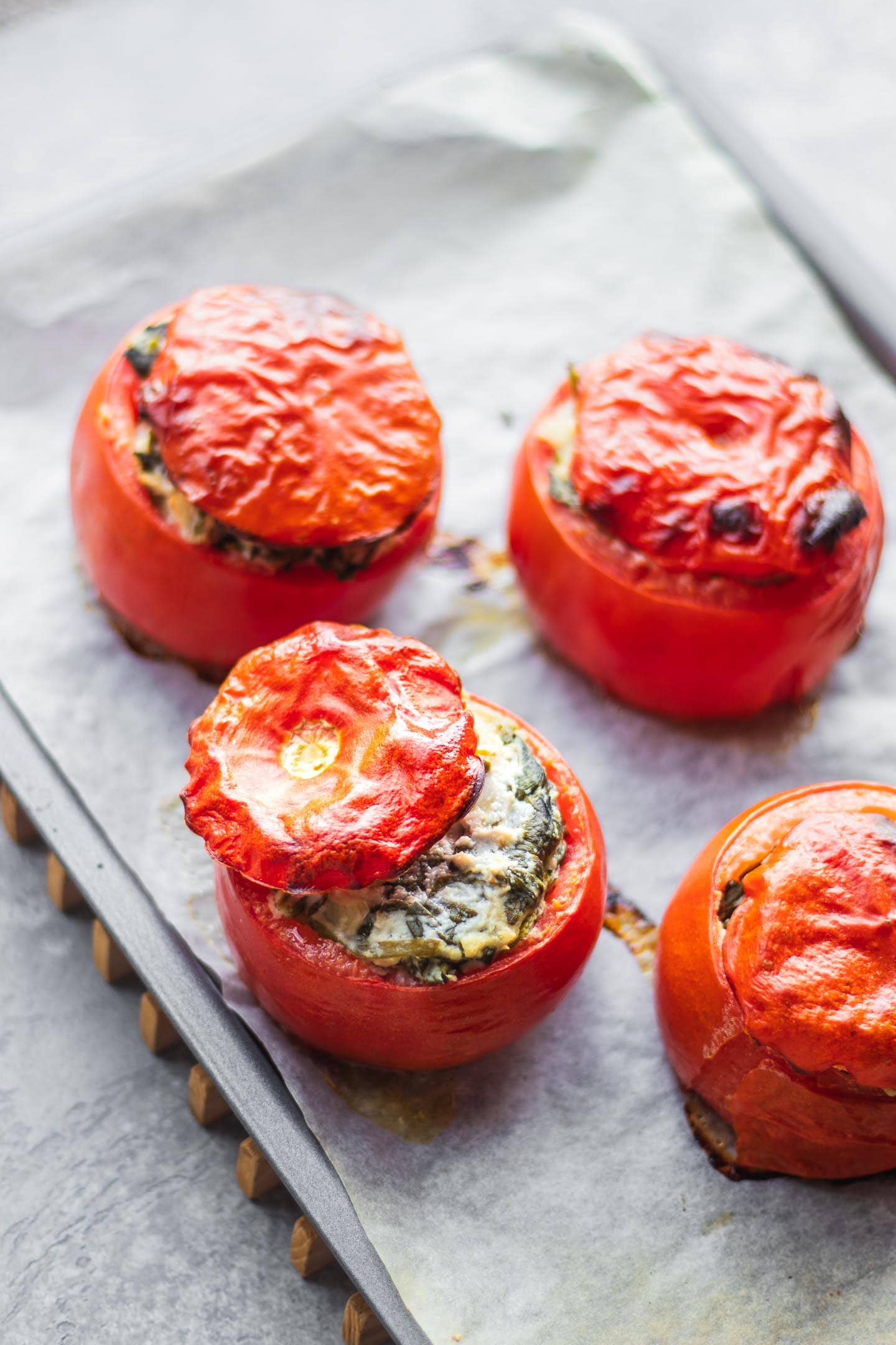 Vegan stuffed tomatoes with creamed spinach on a baking tray