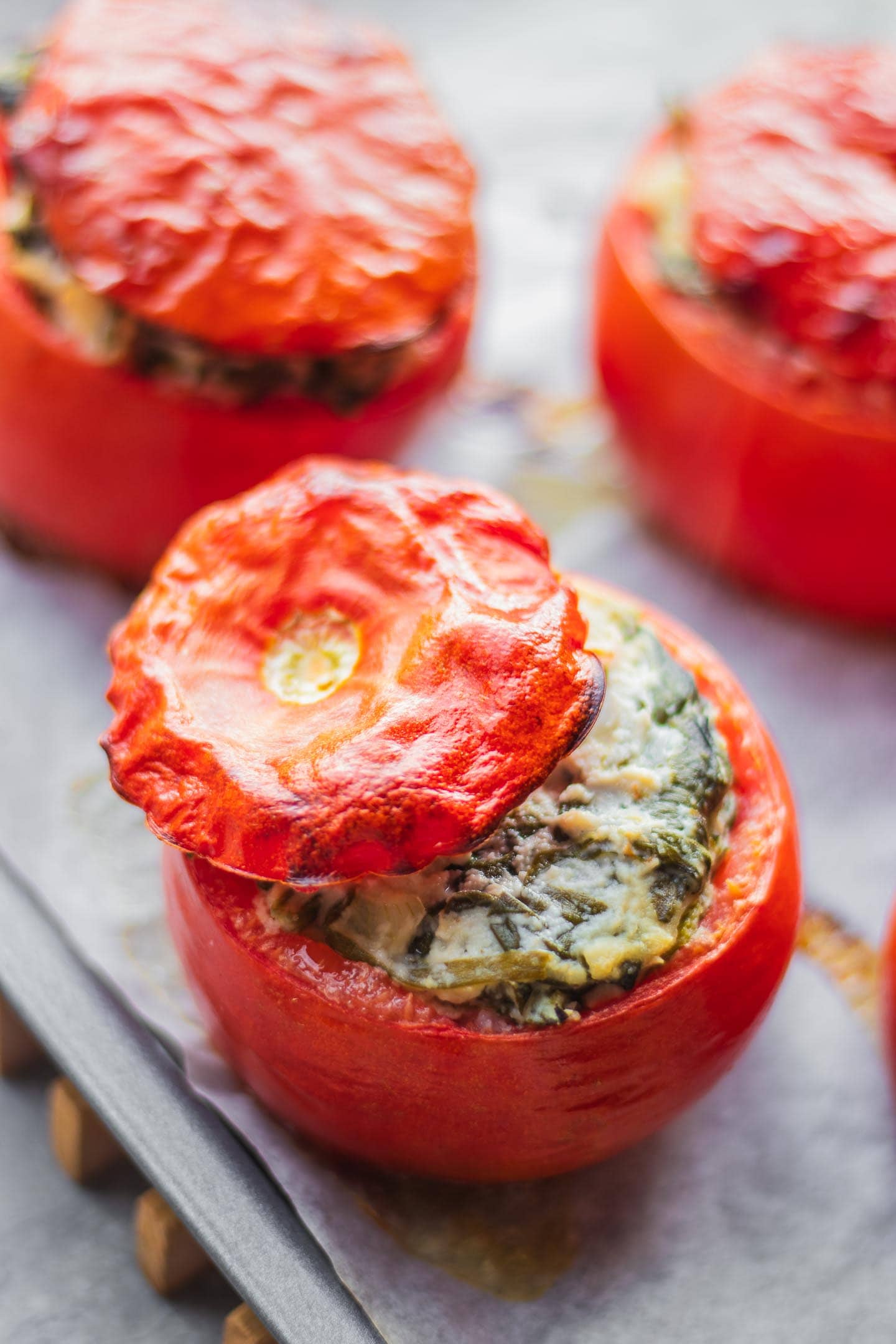 Vegan stuffed tomatoes with creamed spinach on a baking tray