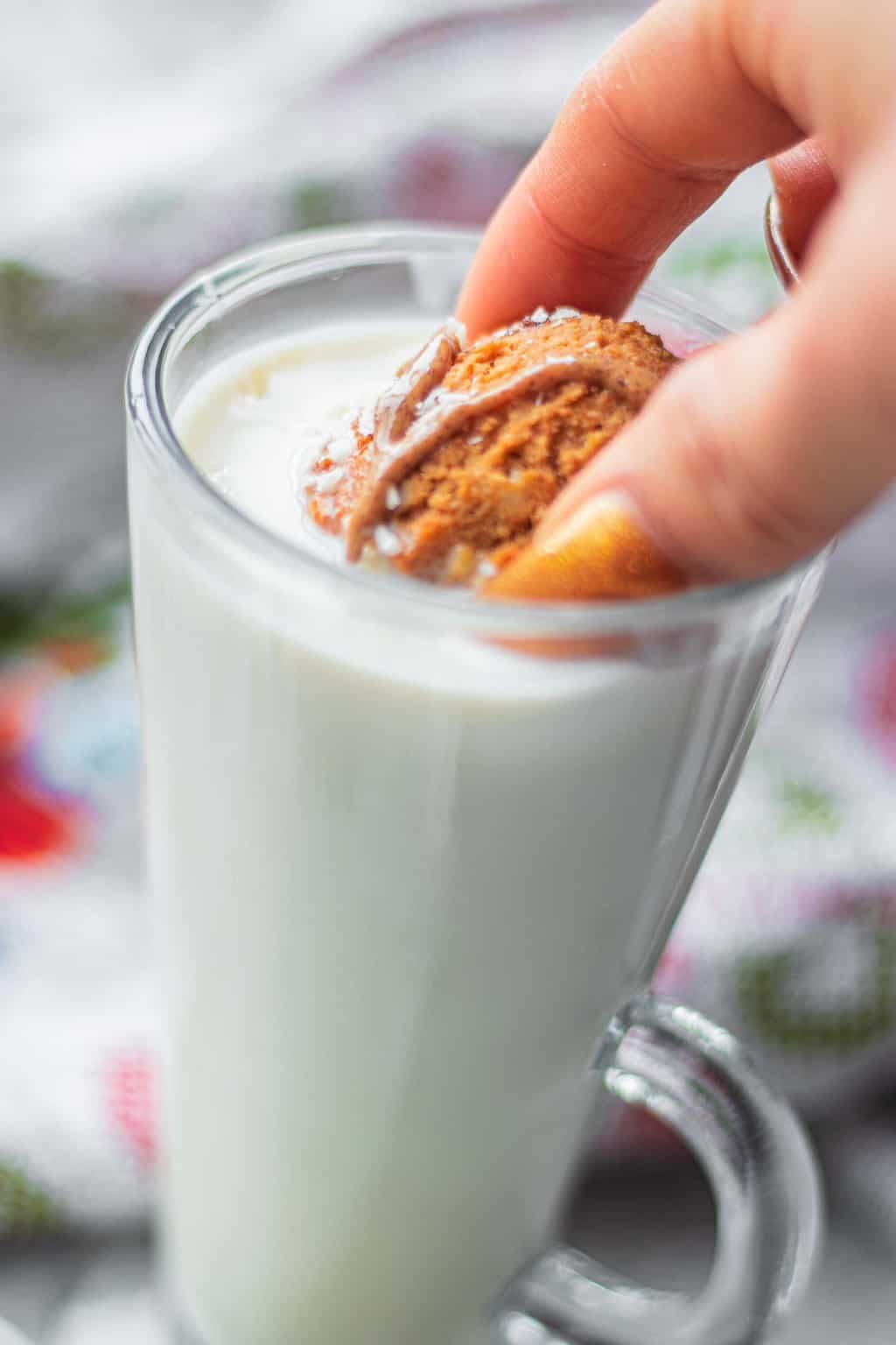 Vegan almond cookie being dipped into a glass of milk