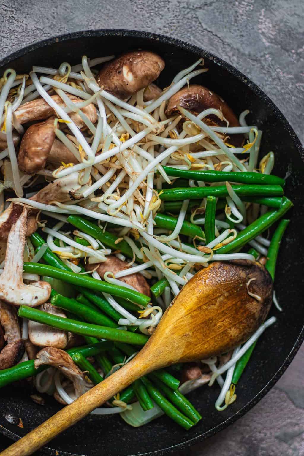 Mushrooms beansprouts and green beans in a frying pan