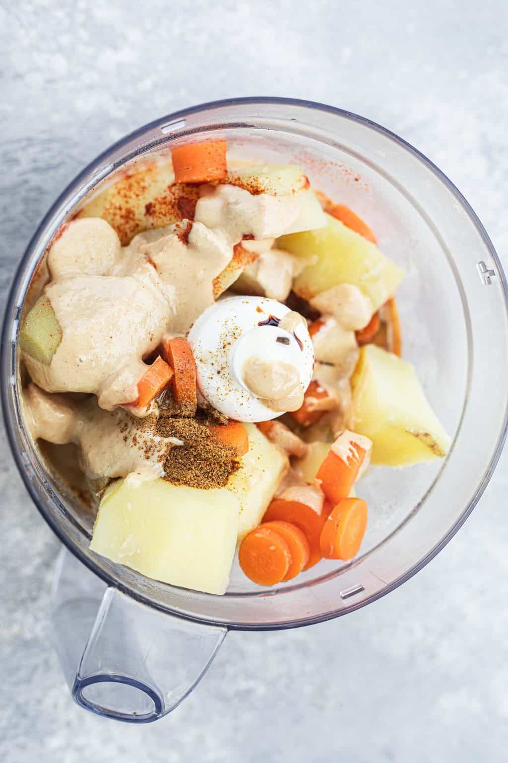 Potatoes and carrots with spices in a food processor