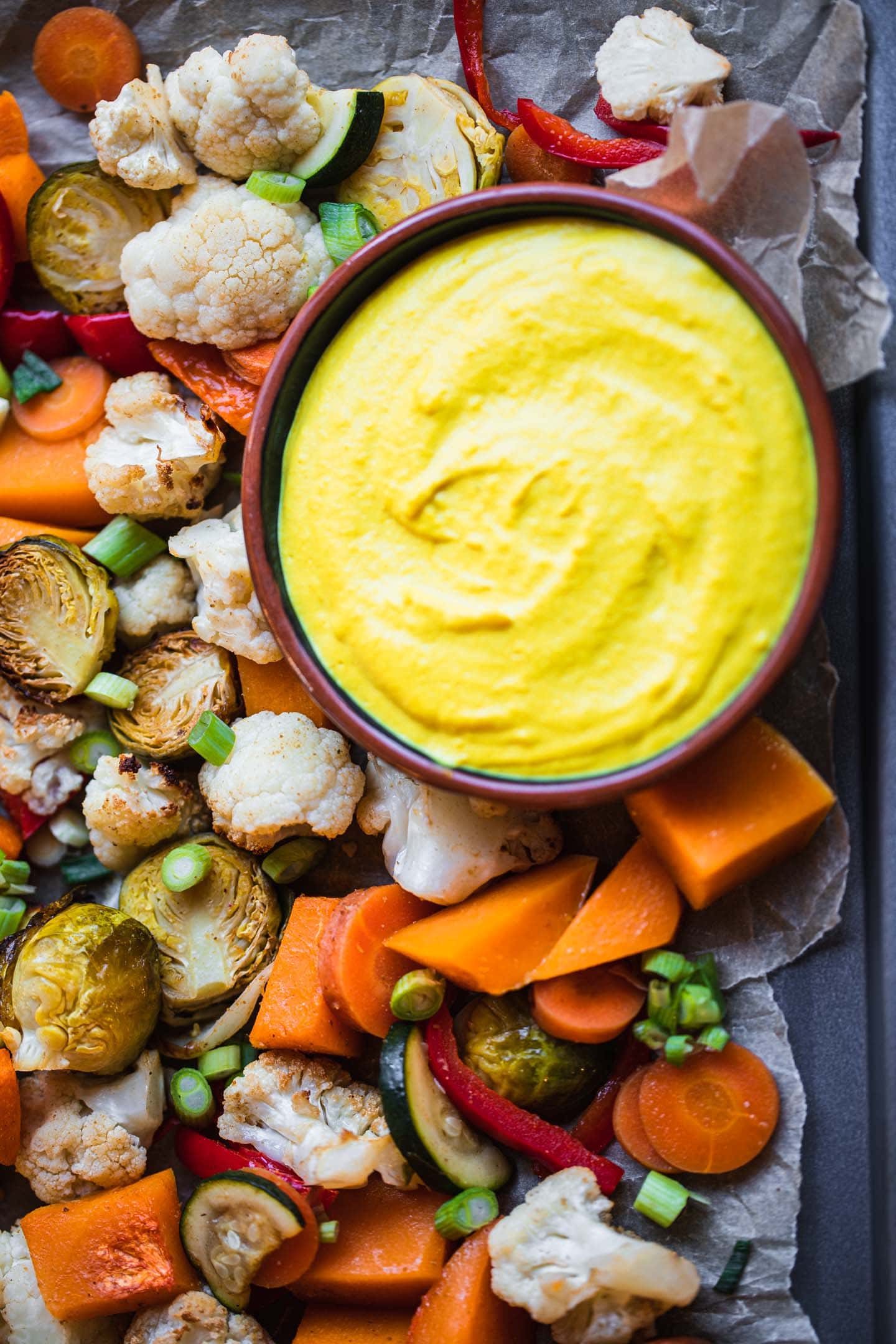 Closeup of Brussels sprouts, butternut squash, cauliflower, carrots, red bell peppers and zucchini on a baking tray
