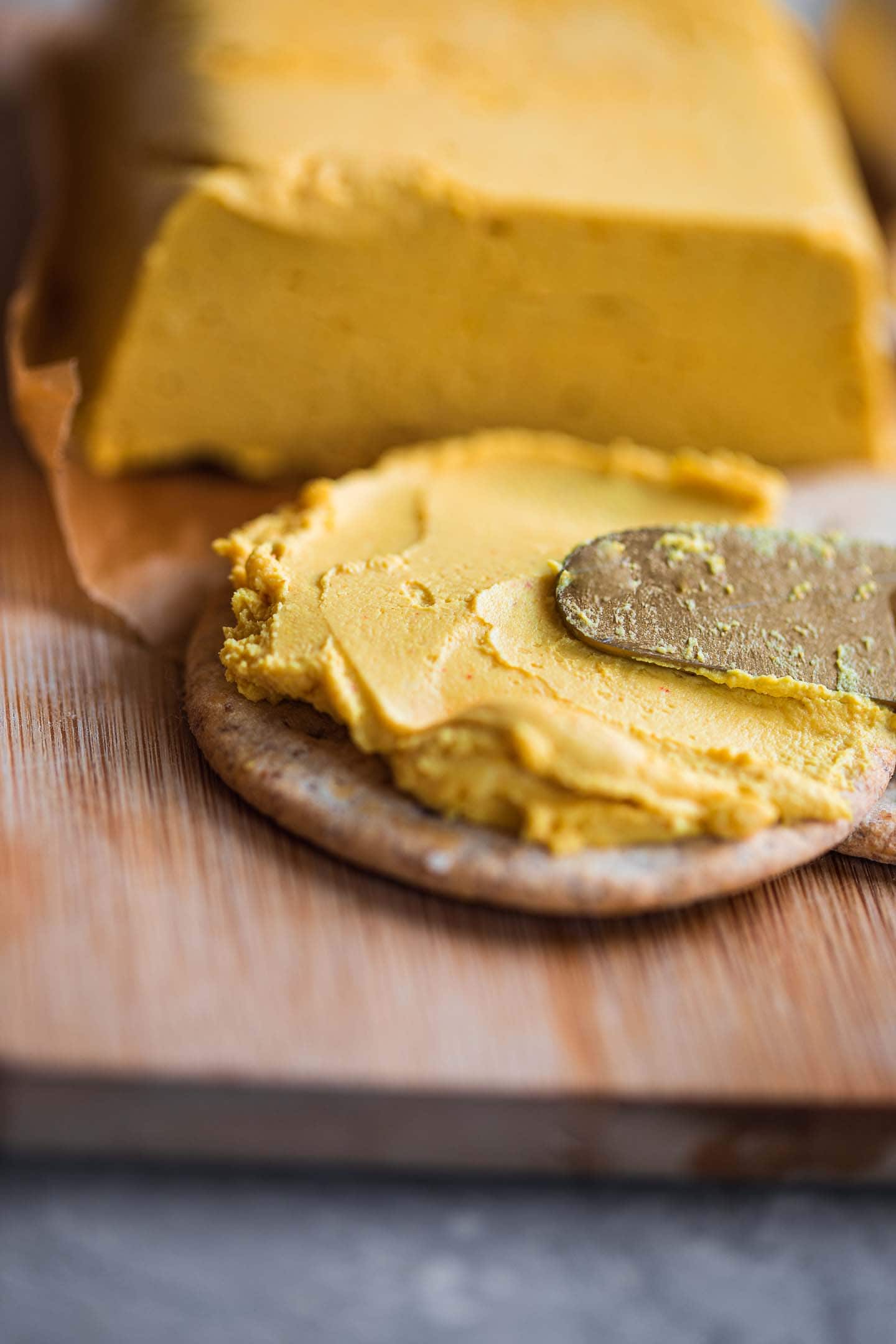 Vegan cheese being spread on a cracker