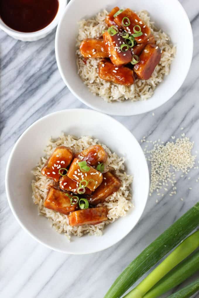 Sweet and sour tempeh served with rice, sesame seeds and spring onions