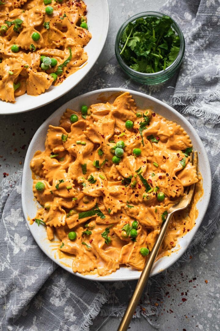 Two bowls of pasta with a red pepper sauce