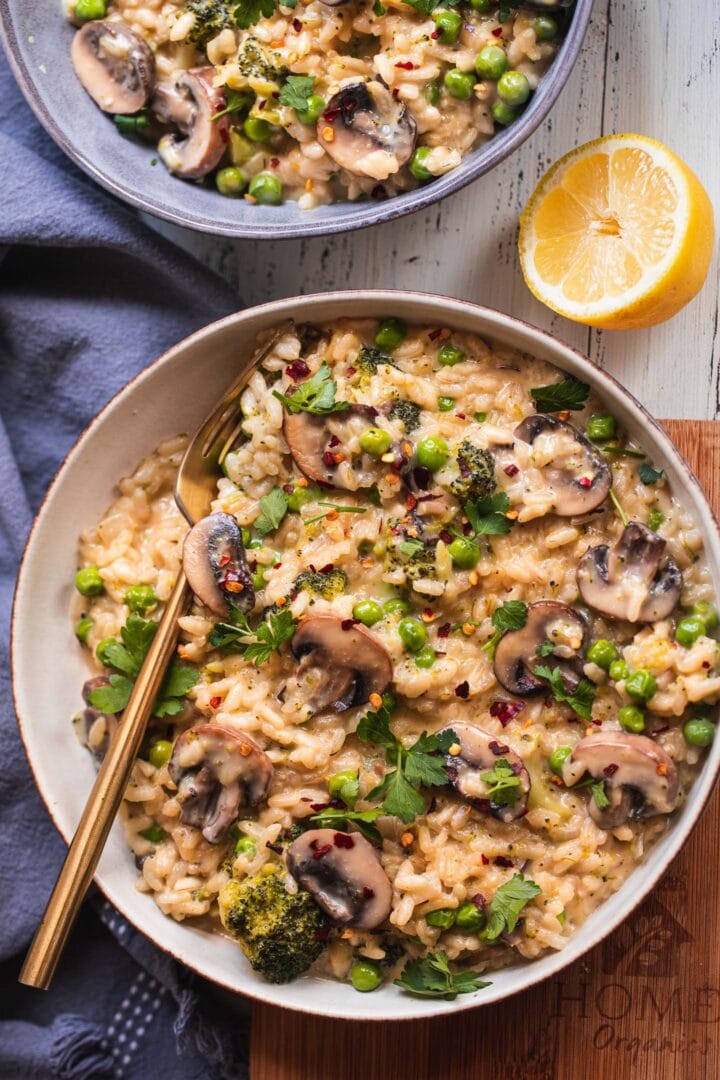 Two bowls of vegan risotto with mushrooms and green peas