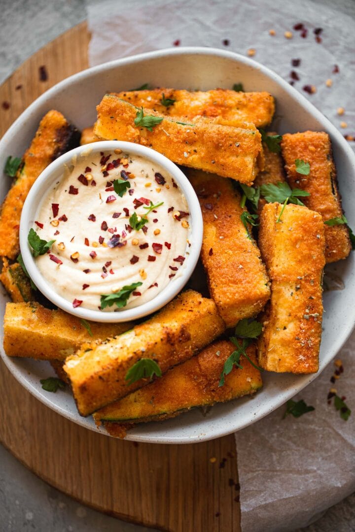 Bowl with breaded zucchini and a vegan garlic dip