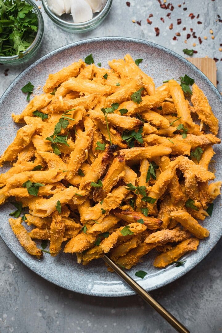 Vegan baked mac and cheese on a plate with fresh herbs