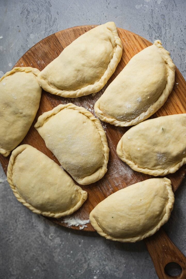 Piroshki on a wooden board before cooking