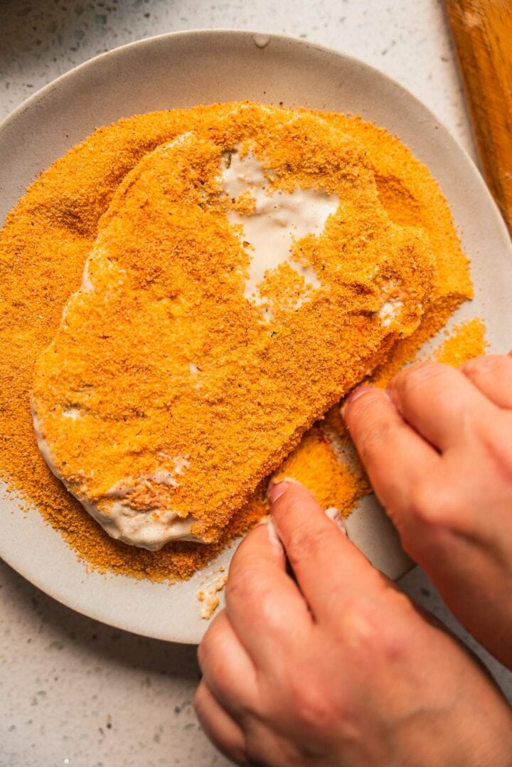 Vegan schnitzel being dipped into breadcrumbs