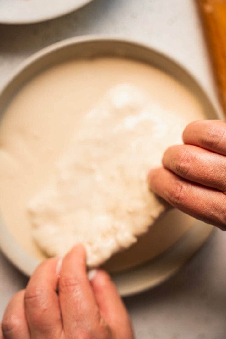 Vegan seitan cutlets being dipped into batter